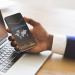 Black businessman checking global financial analytic on smartphone or trading on forex, using cellphone with stock market economic statistic on screen while working in office, creative collage