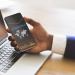 Black businessman checking global financial analytic on smartphone or trading on forex, using cellphone with stock market economic statistic on screen while working in office, creative collage