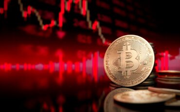 Bitcoin token standing in front of a blurred red price chart.